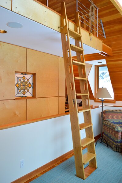 A ladder from the carriage house's living room leads up to a loft bedroom. 