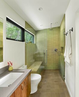 A long, linear window brings light into the Heath Ceramics tile-covered shower, which is curbless, so as to accommodate aging-in-place.
