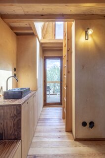 The tree house's floors, walls, ceiling, and built-in furniture are wrapped in wood, connecting the interior to the outdoors.
